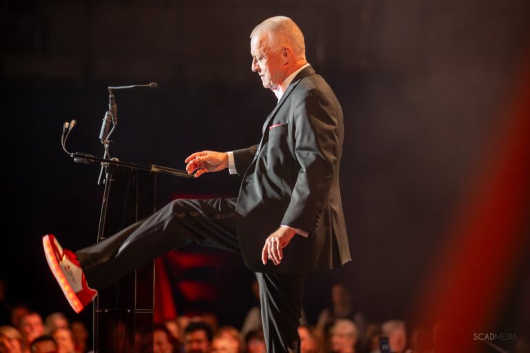 Speaker kicking up a light-up red shoe on stage